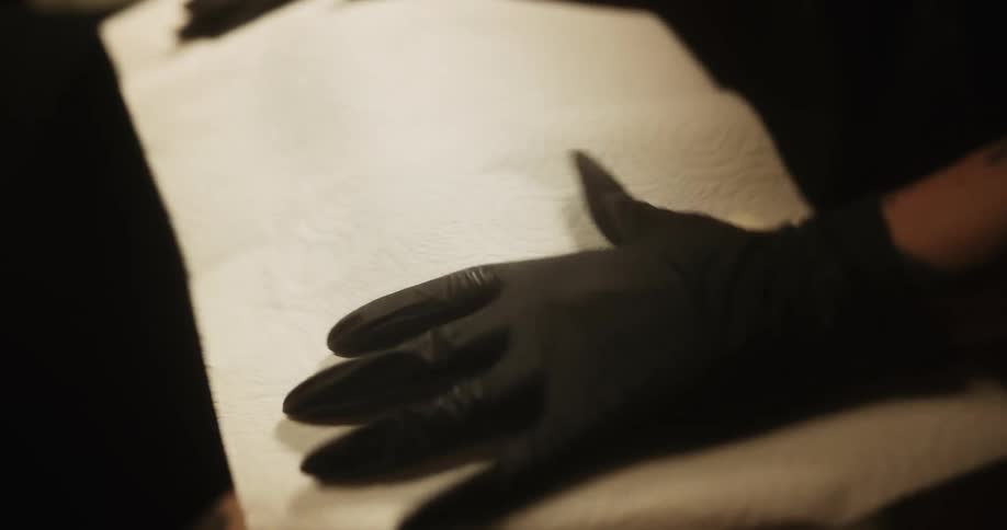 A tattoo artist toweling off a fresh tattoo a woman is getting on her hip and thigh