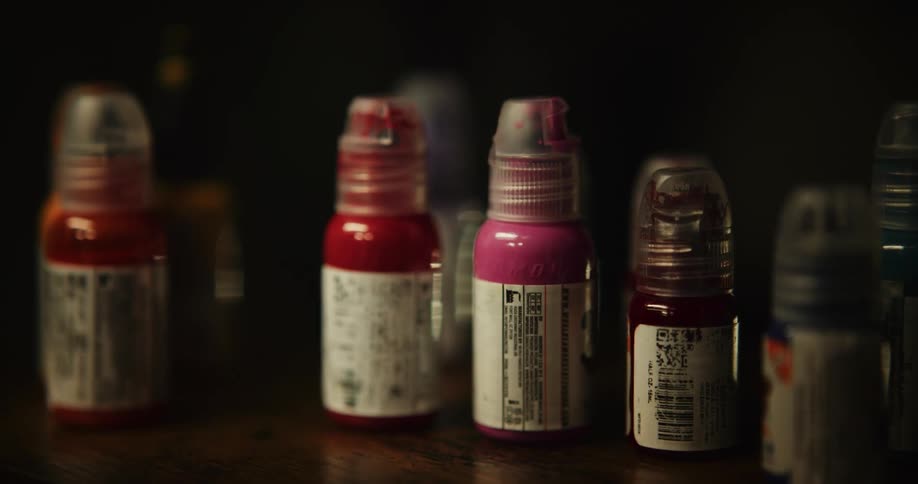 Multiple paint bottles sit on hardwood shelf