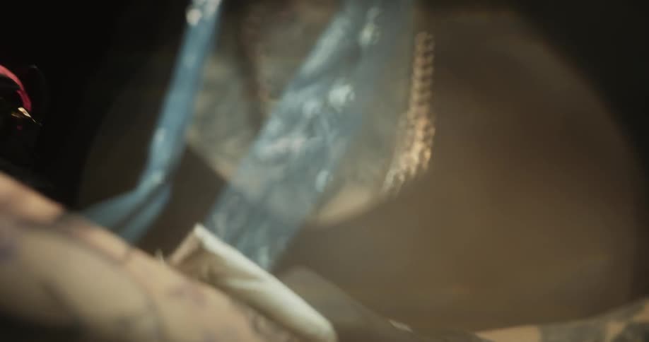 Close up of a tattoo artist with colorful hair working on the skin of a client