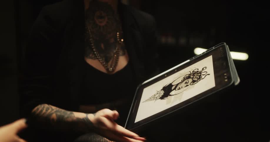 A woman is sitting across from another woman that is off camera and she is showing her an image on a tablet