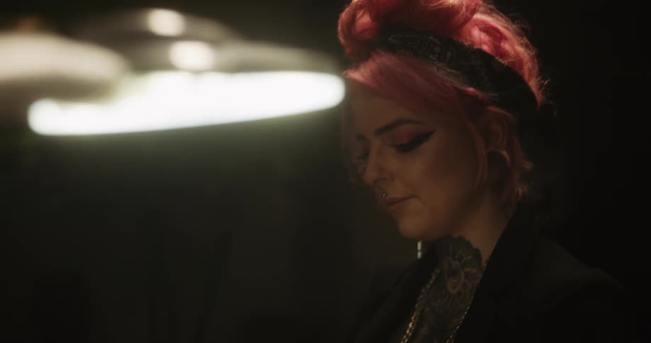 A female tattoo artist putting on gloves next to a client