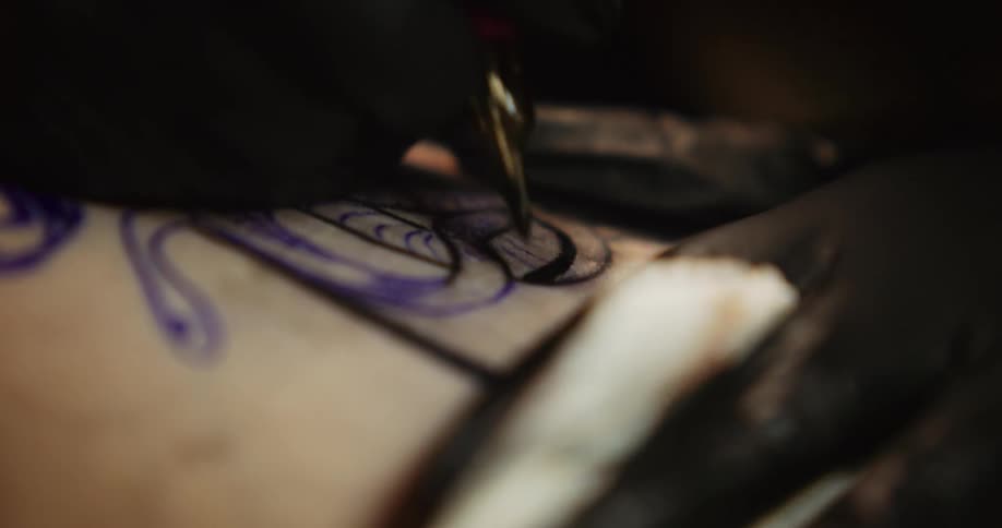 Close up of an artists using a tattoo machine on the skin of a customer