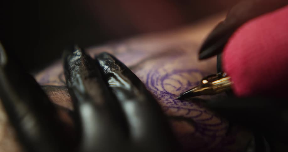 Close up of an artists using a tattoo machine on the skin of a customer