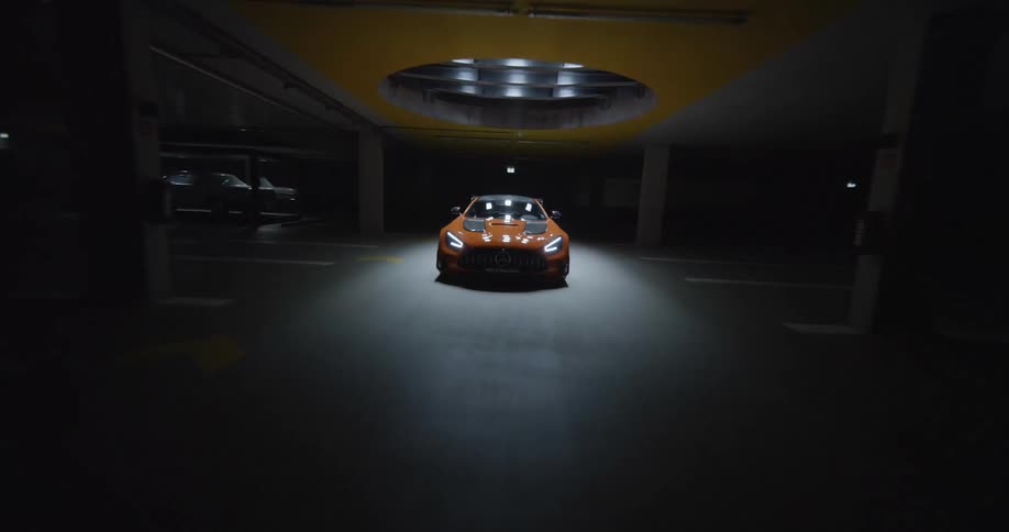 An FPV drone flying over a luxury sports car in a showroom at night