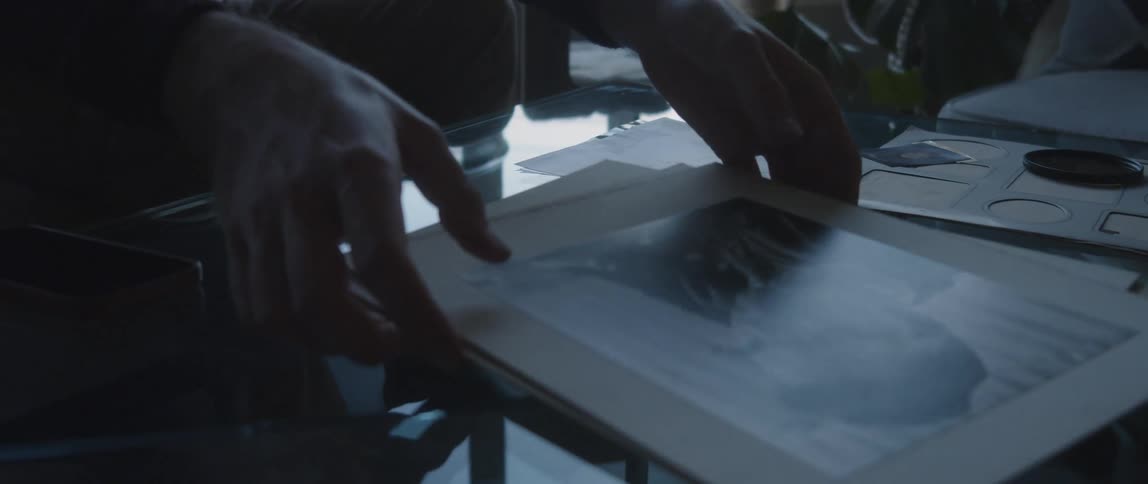 A man goes through a stack of photographs on his coffee table