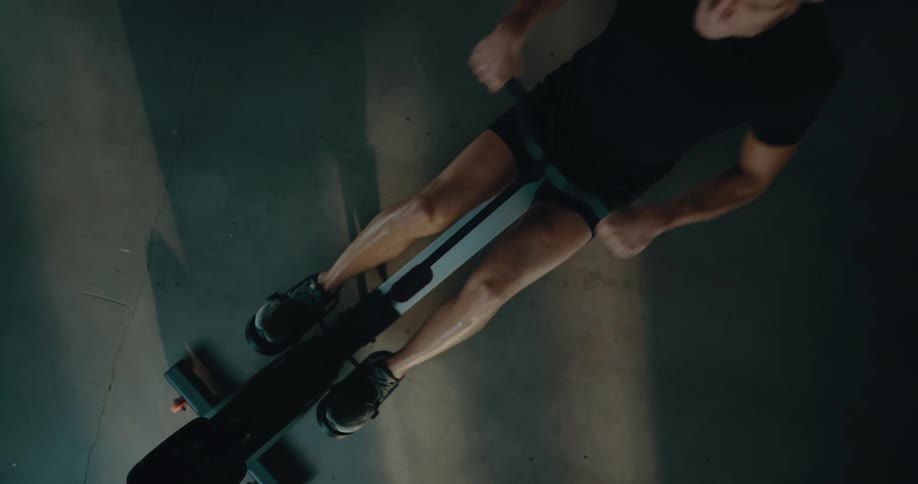 Top down view of a strong muscular man sweating while working out on a rowing machine