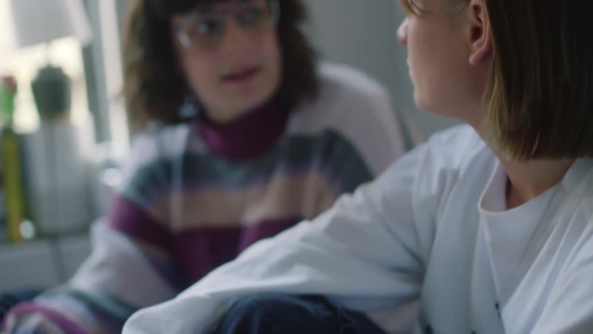 Two girls talk while sitting in the bed