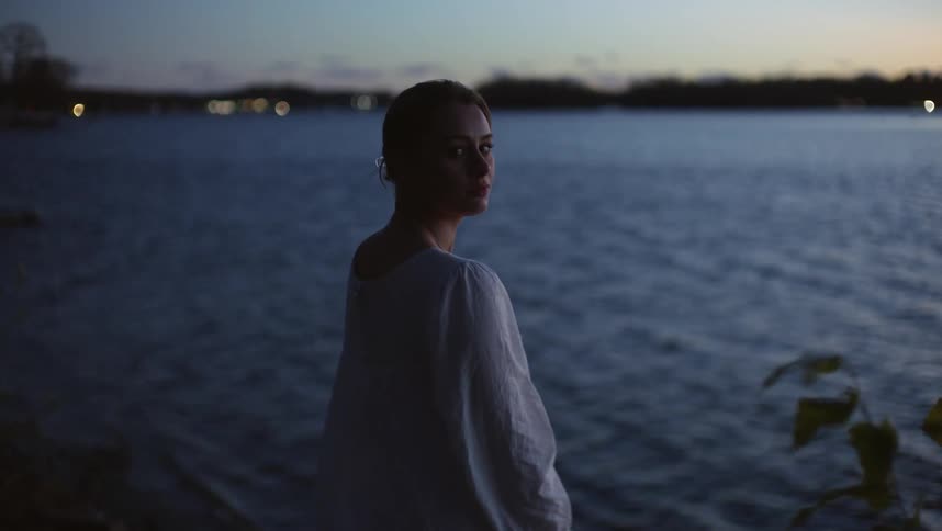 A woman looks around by the lake