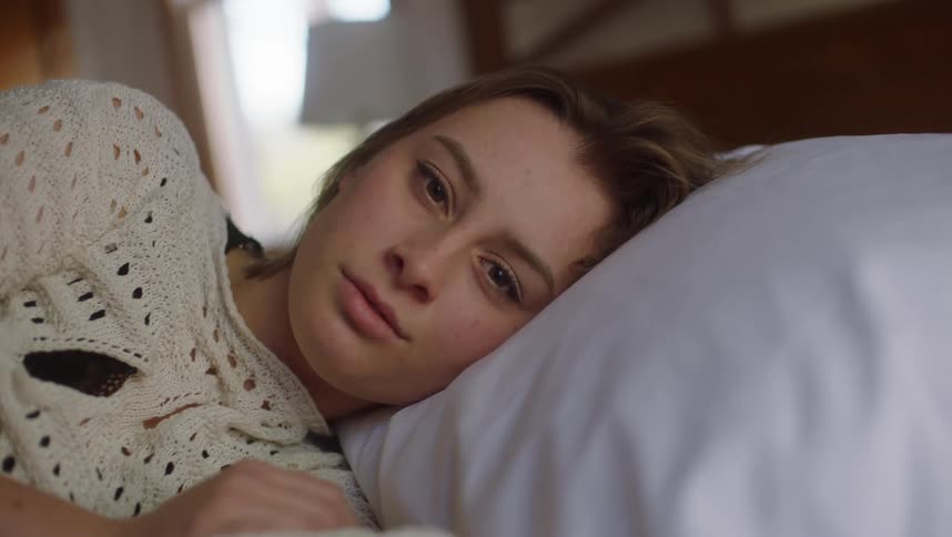 Young woman resting in the bed looking at the camera