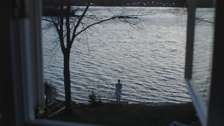 A woman is watching the lake outside the window