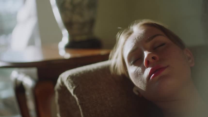 Sunlight shines on a woman sleeping on her living room couch