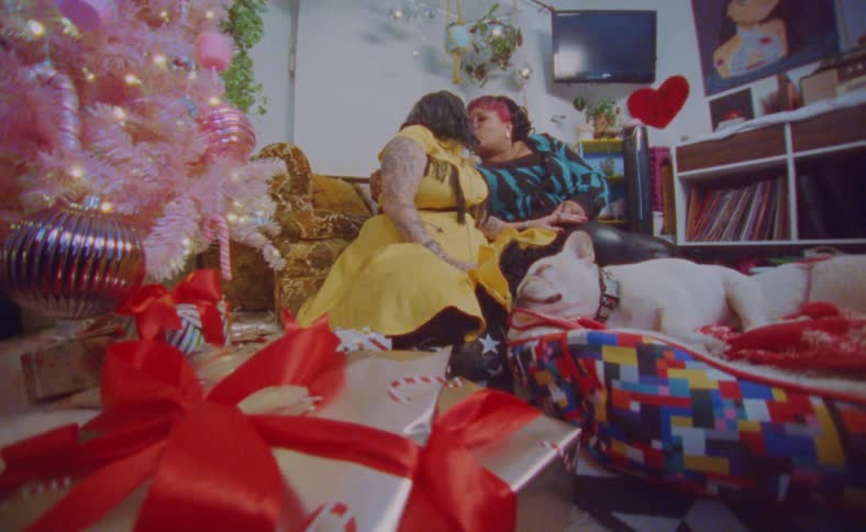 Young happy couple sitting next to a colorful christmas tree with their dog