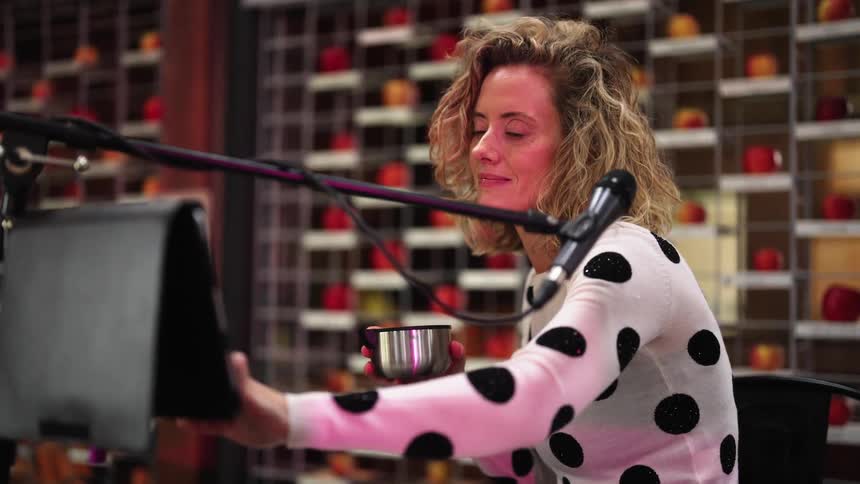 Woman makes selections on touchscreen sitting near microphone while holding a bowl