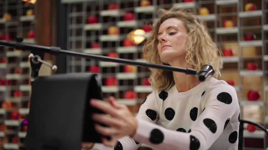 A woman is setting up a tablet computer under a microphone stand