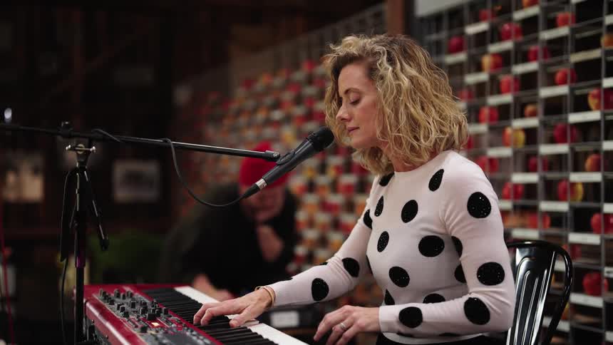 Female singer playing a keyboard performs on stage on a small venue