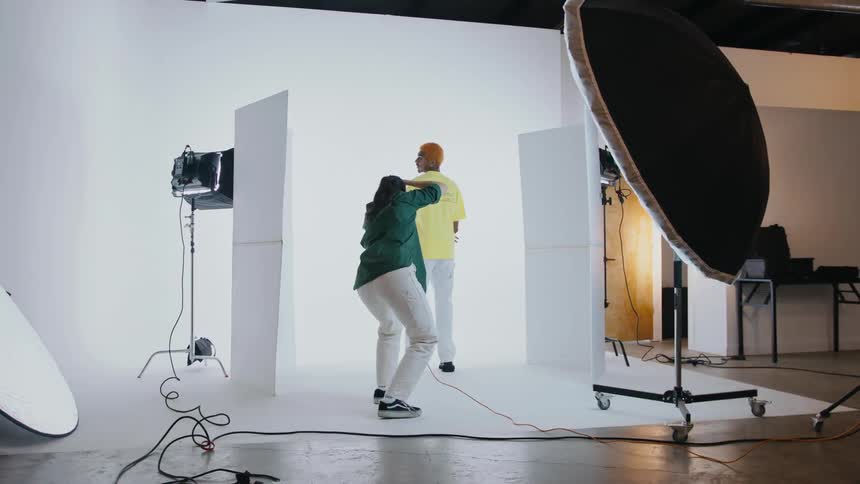 Male model with red hair yellow t shirt and white pants poses for the photographer in the studio