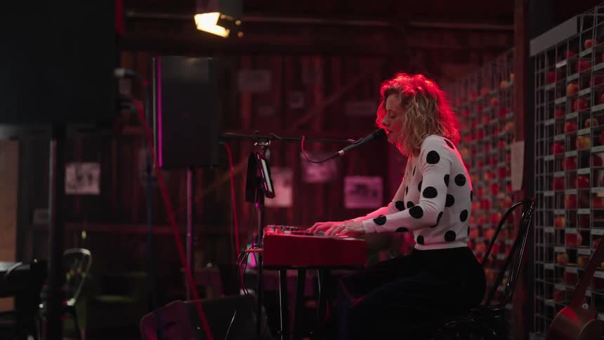 A woman sings and plays the keyboard in a bar
