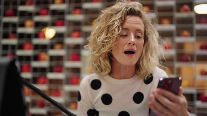 Young blonde woman wearing a polka dot shirt talking on the phone