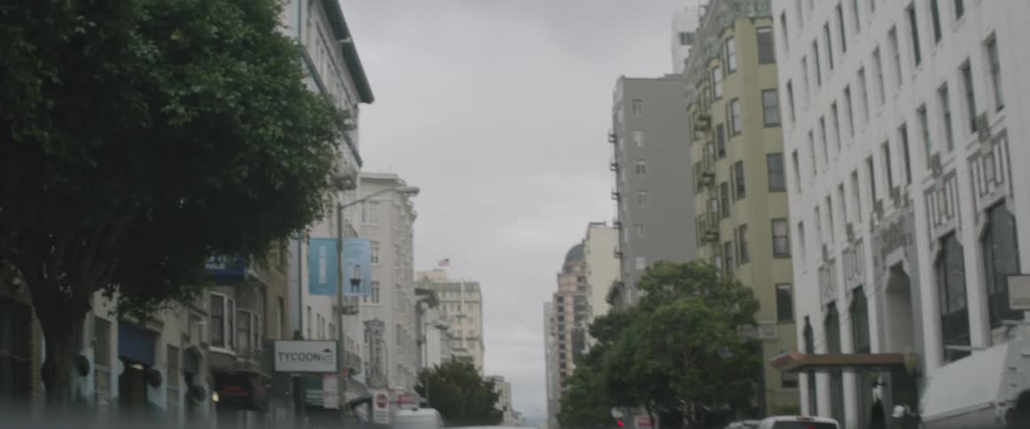 Cars move down this street lined with buildings