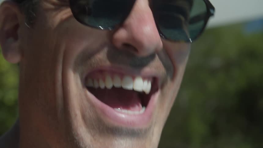 Sunlight and water reflcton on the face and sunglasses of man as he laughs
