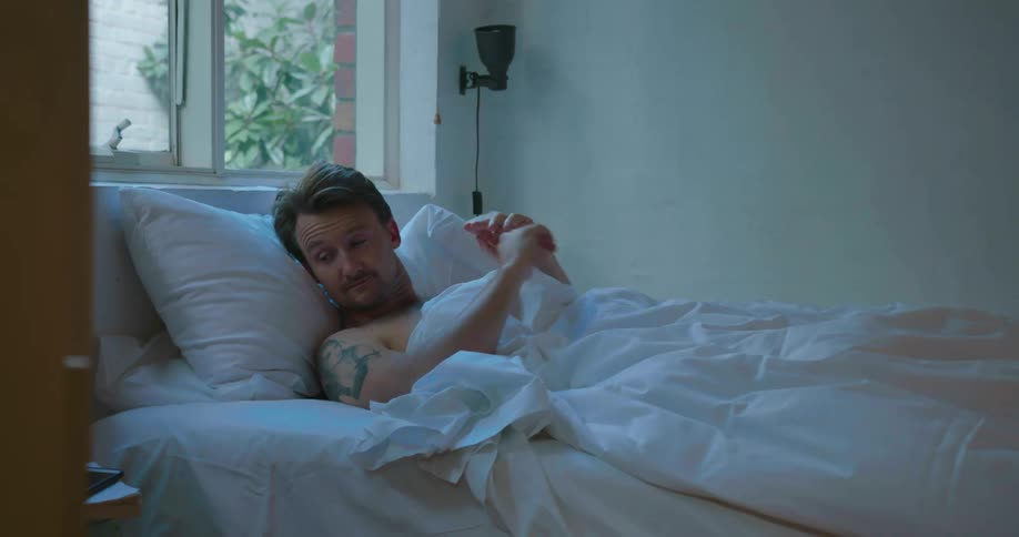 Man wakes up and rubs eyes before turning off alarm