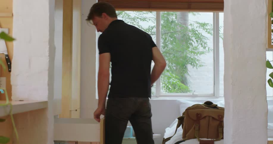 A man packs a duffel bag then picks it up and walks out of the room