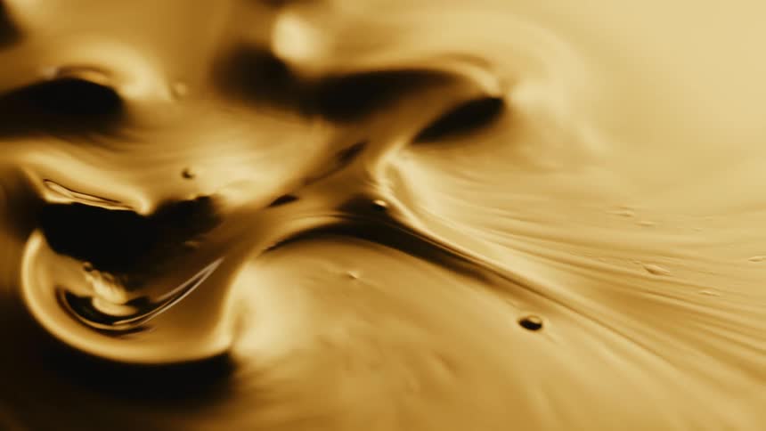 Light shines on a gold liquid substance as it ripples and moves