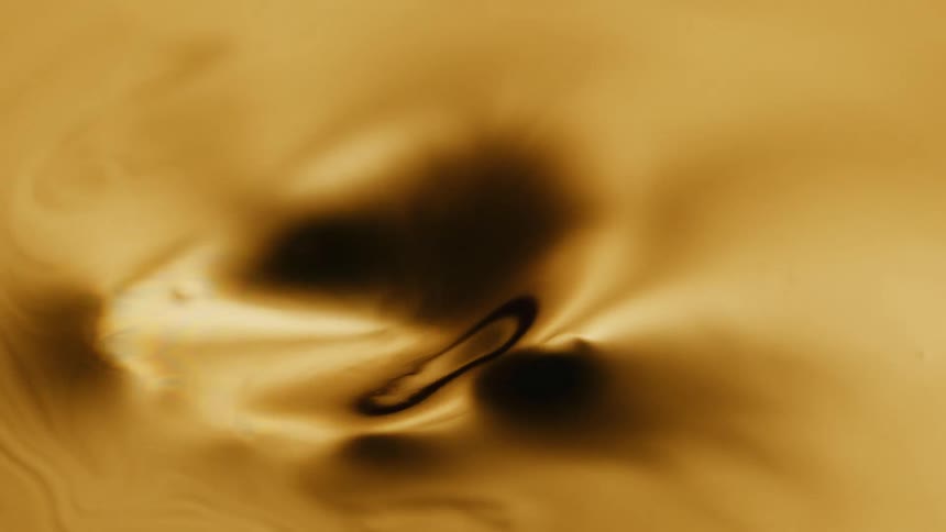 Light shines on a liquid gold substance as it ripples and moves