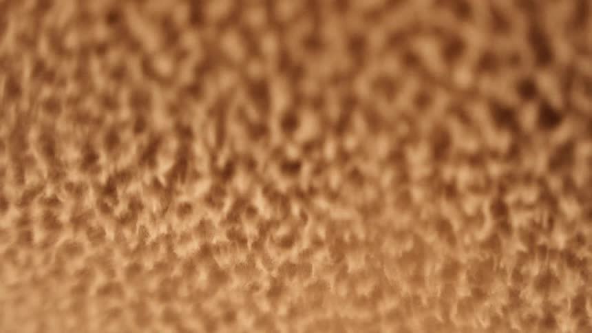 A gold substance vibrates and pulsates as it becomes a boiling splashing liquid vigorously moving