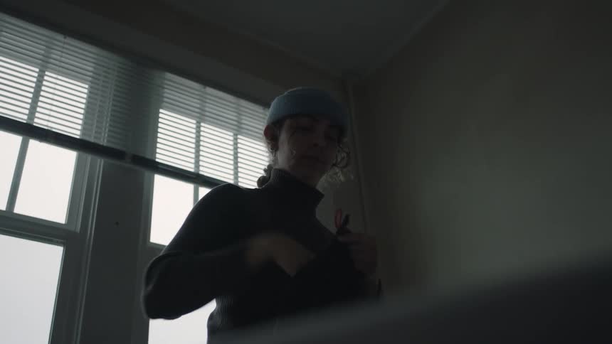 Woman enters a room and loads her backpack with clothing for a hike