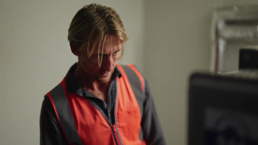 A man pushes buttons as he maintains equipment while working