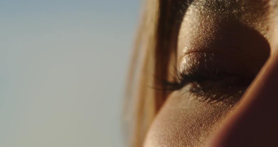 A woman brushes her hair away from her eye