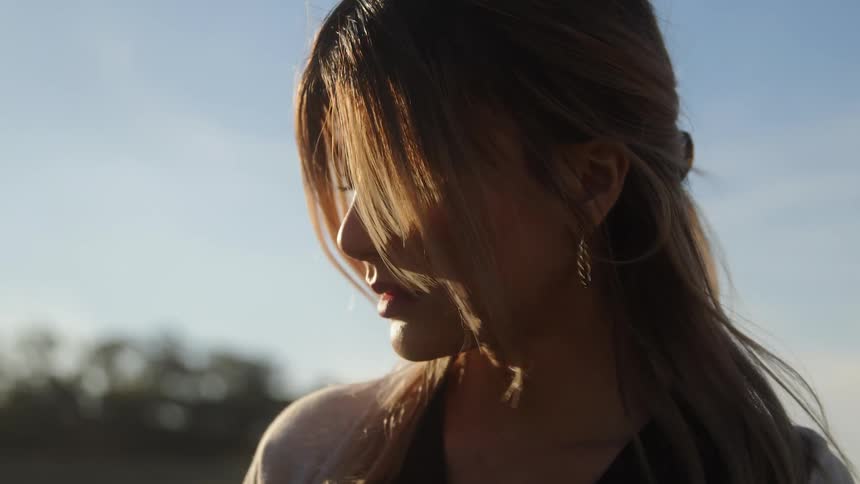 Woman standing outdoors with wind blowing through her hair