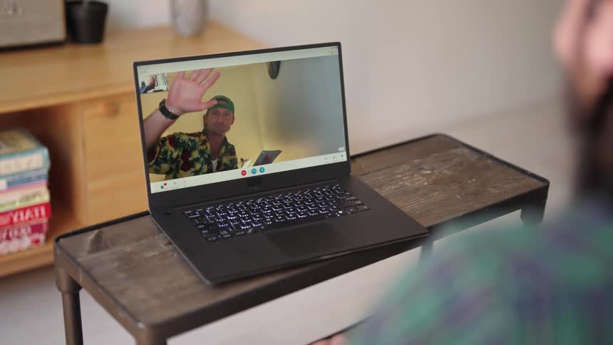 Man logs into a video call with a friend on a laptop at home