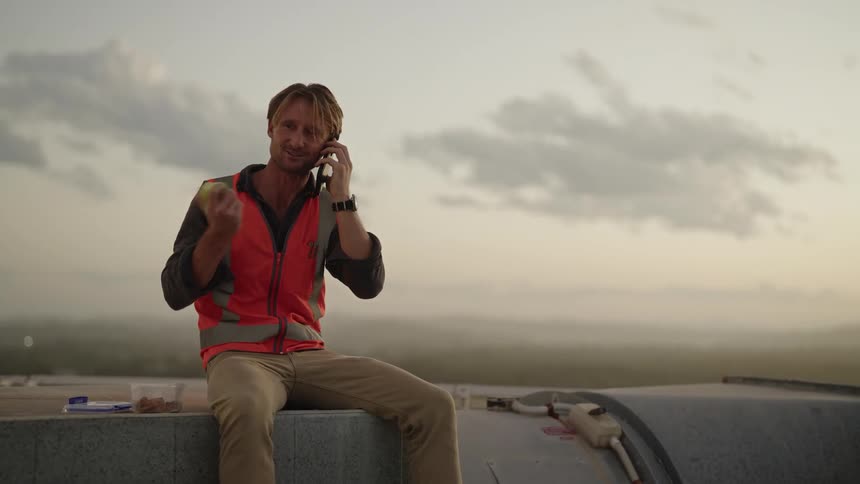 A man is eating an apple and talking to someone on the phone