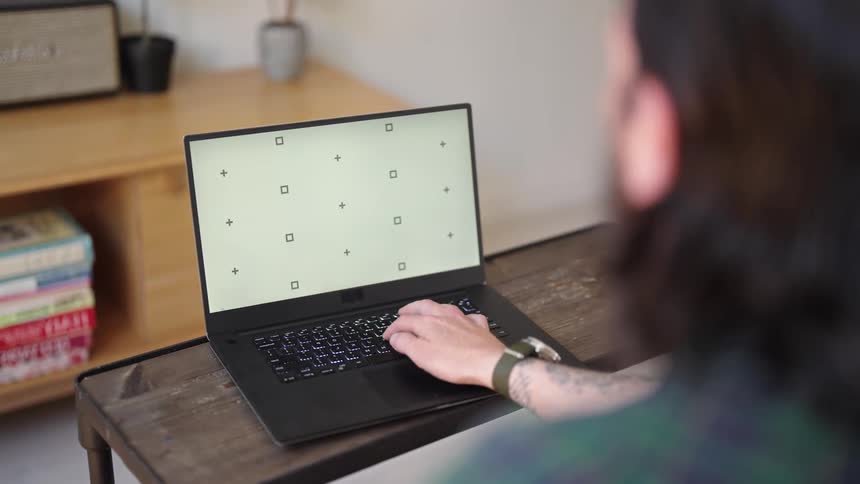 Man typing on laptop working remotely in living room