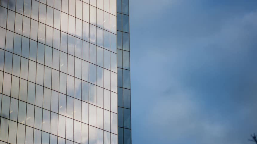 Reflective surface of skyscraper reflects cloudy sky