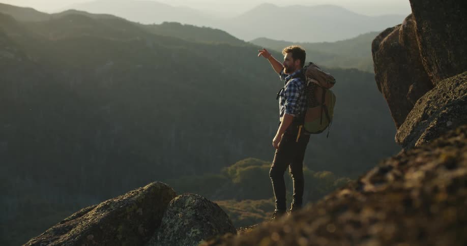 A young man is hiking and looking at the mountains