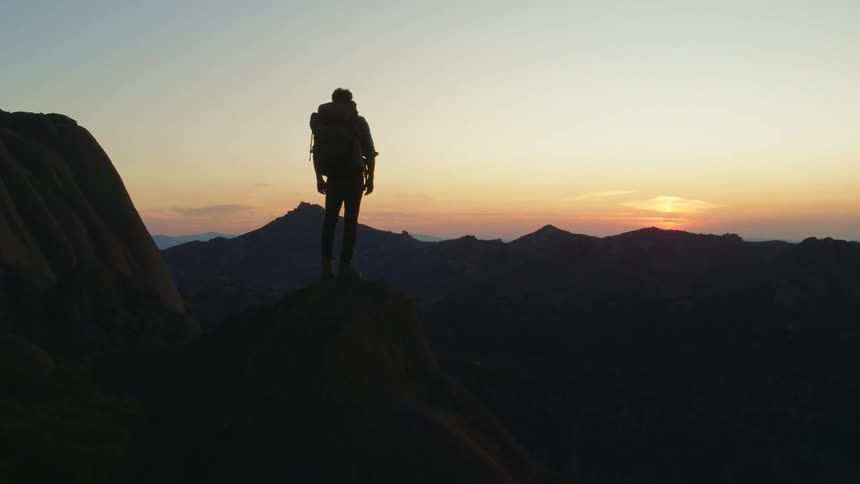 There is a young man that is hiking in the middle of the day time
