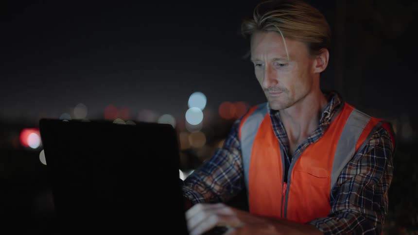 An older man is outdoors and is going on his laptop