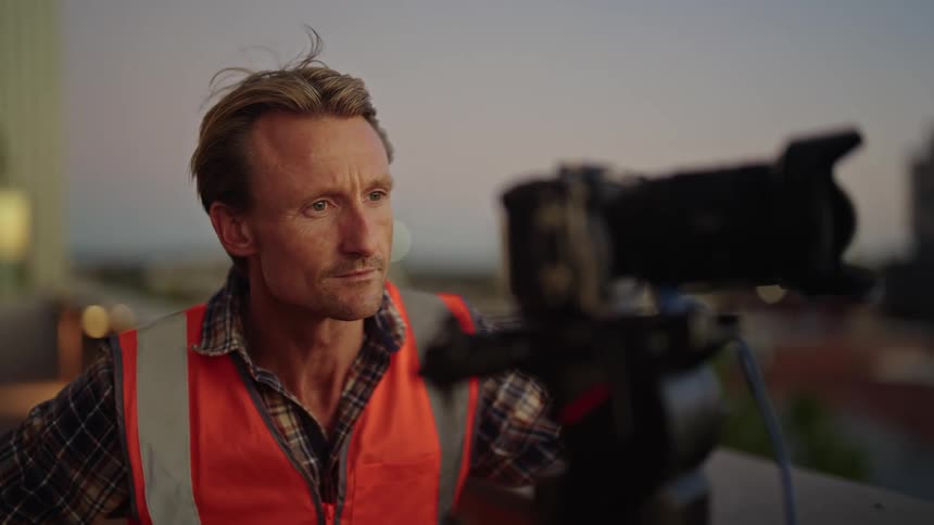 A man is adjusting and pointing a camera