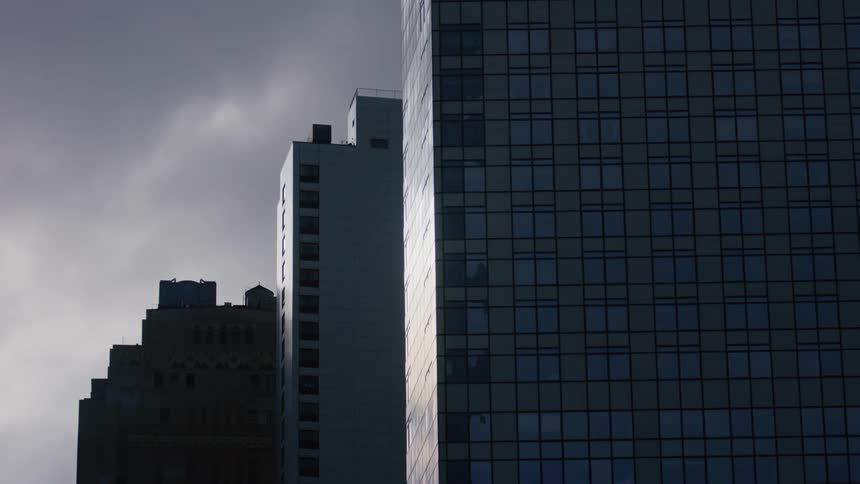 Three large buildings are shown with the sky showing dark clouds moving in