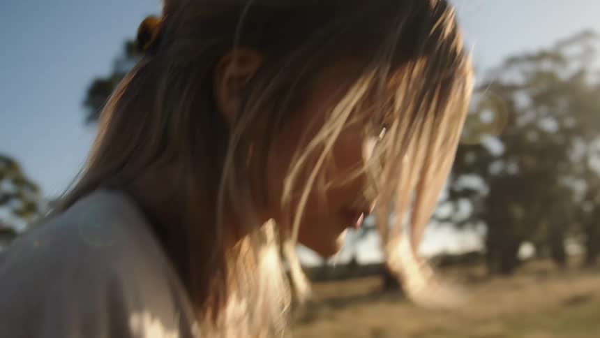 The sun shines brightly on a teenage girl as she walks through a field