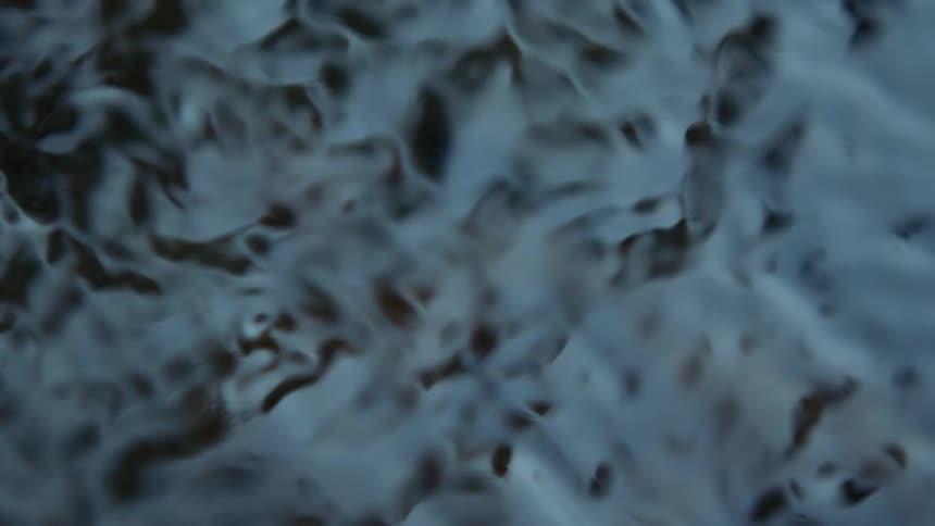 Light shines on the surface of water and reflects light as it ripples and moves