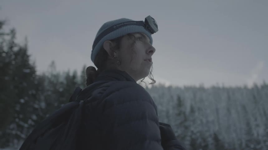 Woman looks at view of snowy woods on a hike
