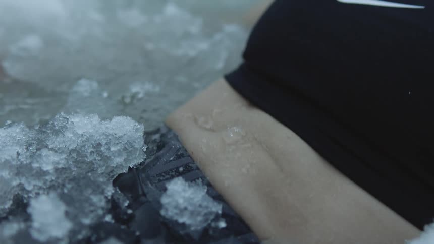 A persons torso breathing heavily submerged in an ice bath