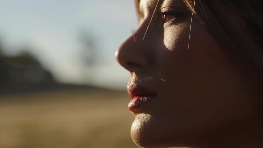 Side profile of woman with brown hair looks into space in the field