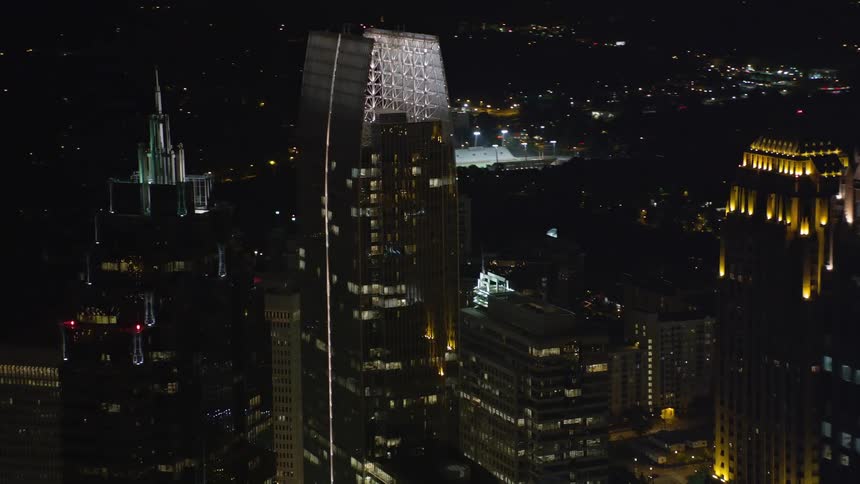 A stunning aerial footage showcases the GLG Grand and other skyscrapers towering over a metropolis during a clear night in Midtown Atlanta
