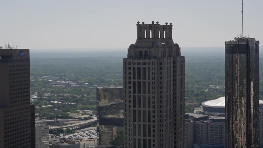 Aerial footage orbits the top of 191 Peachtree Tower showcasing the tall skyscrapers in downtown Atlanta during a sunny summer day
