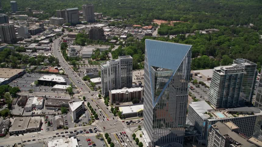 Aerial footage approaching Terminus Atlanta and tilting down to a birds eye view of Buckhead GA showcasing modern high-rise buildings and skyscrapers during a sunny day